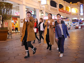 two young women wearing Santa hats while walking on the Sun Wen West Road Pedestrian Street in Zhongshan