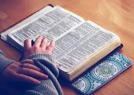 Hombre con una mano en la biblia abierta estudiando