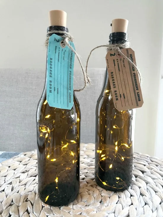 Recycled beer bottles with vintage tags and fairy lights on a cork