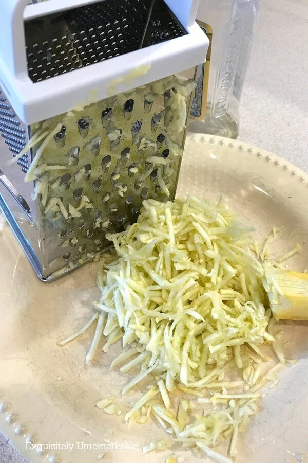 Grater with shredded squash on a plate