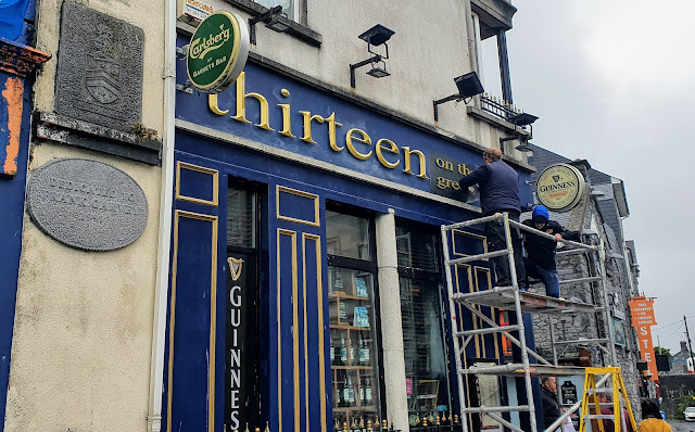 Workermen installing new signs saying 13-on-the-green in Garvey's Inn hotel in Eyre Square, Galway