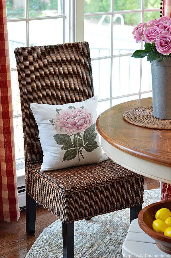 Wicker Parsons Dining Chair with floral pillow around table