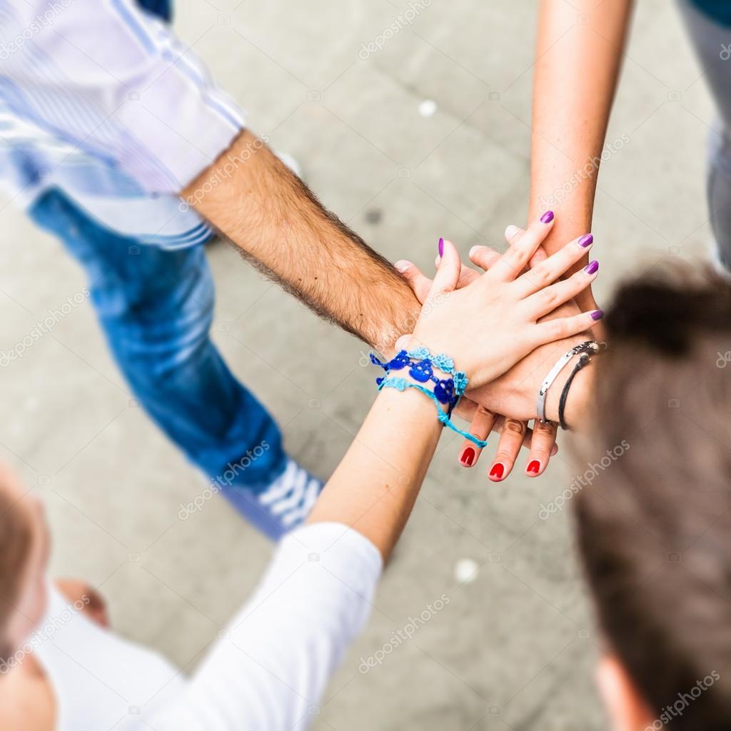 Younger hands. Люди сложили руки вместе. Молодежь руки. Пять человек держатся за руки. Вместе для большего.