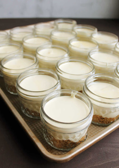 mini cheesecake jars ready to bake tray full of cheesecake mixture in jars ready to bake