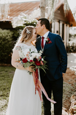 bride and groom kissing at the acre orlando with bouquet