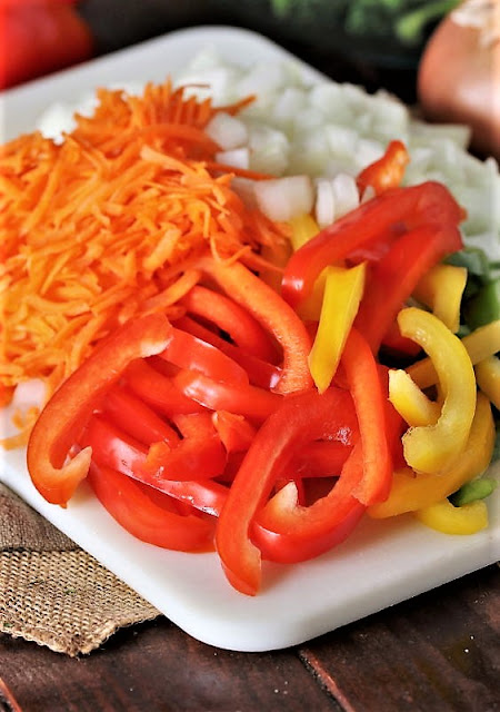 Sliced Red and Yellow Bell Peppers and Shredded Carrots on Cutting Board Image