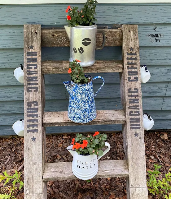 Photo of a ladder decorated with an Organic Coffee stencil, coffeepots with impatiens, and coffee cups