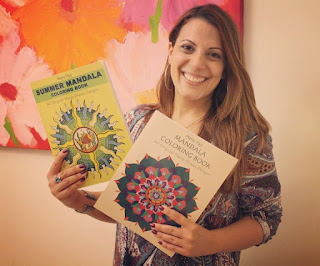 this is the image of a smiling lady, a mandala artist, holding in her hands two mandala coloring books and wearing a boho dress
