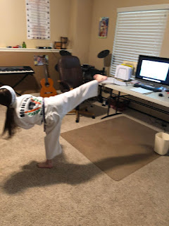 Martial arts girl doing a sick kick while remote learning at home