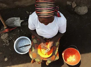 South African woman grinding corn into cornmeal for dinner