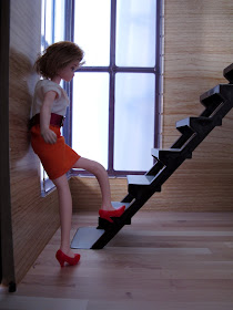 A doll at the bottom of the stairs of the modern Lori Loft to Love dolls' house.