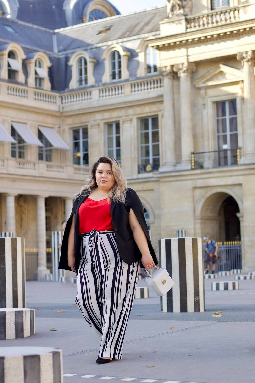 Chicago Plus Size Petite Fashion Blogger, influencer, YouTuber, and model Natalie Craig, of Natalie in the City, reviews Marée Pour Toi's Black and White Striped Pants, Red Washed Silk Charmeuse Tank, and Open Sleeve Blazer while visiting Paris, France and Les Deux Plateaux (also known as the Colonnes de Buren or stripe pillars) in Palais Royal.
