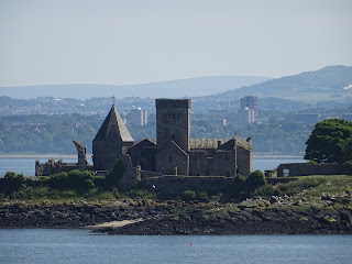 A photo of Inchcolm Abbey, a ruined church sitting on Inchcolm Island, with the Forth and the buildings of Edinburgh in the background.  Photo by Kevin Nosferatu for the Skulferatu Project.