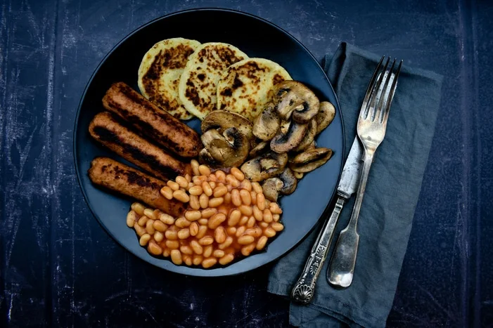 full cooked vegan breakfast - potato scones, veggie sausages, mushrooms and baked beans
