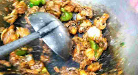 Stir frying chilli mushroom in wok with laddle