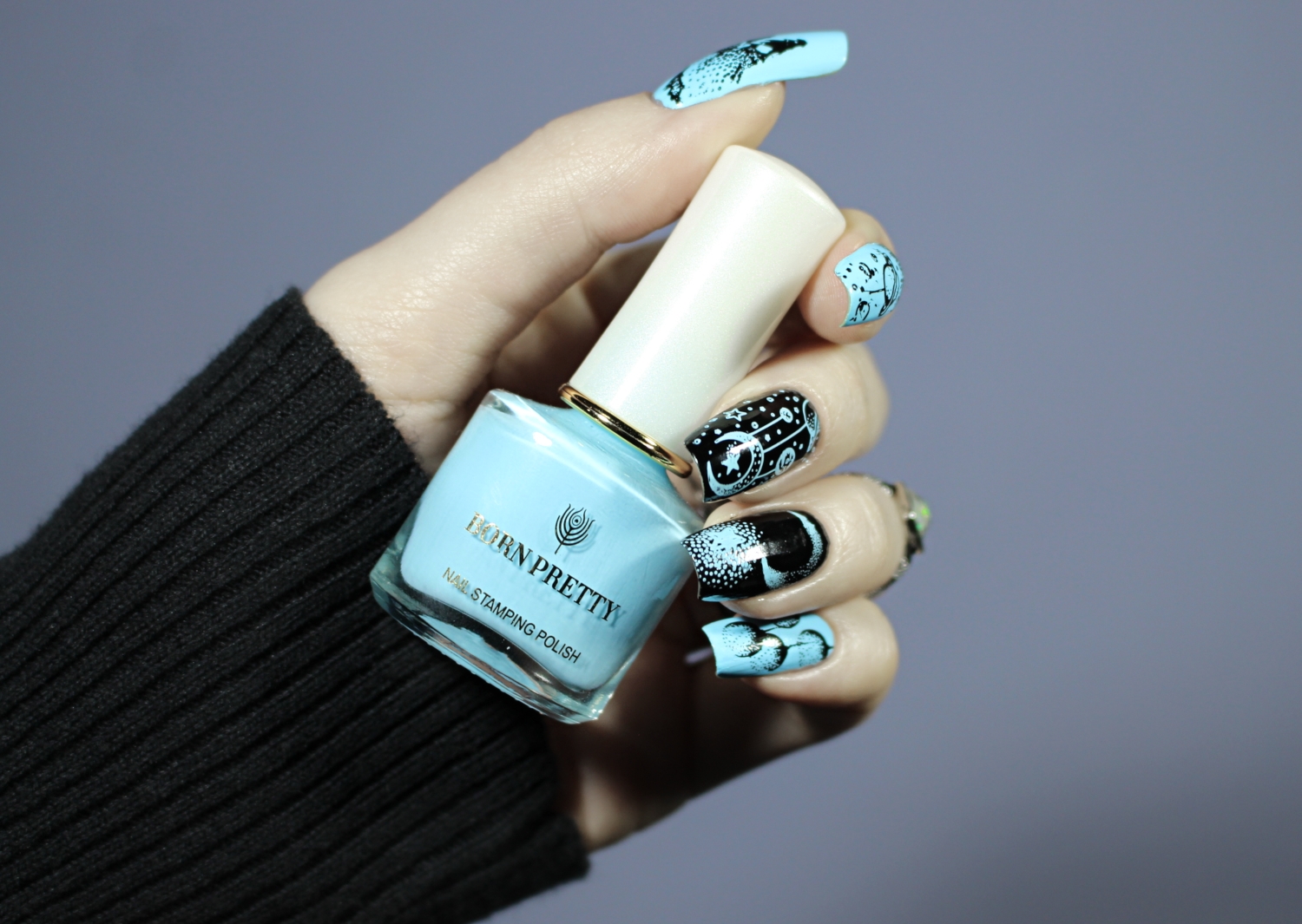 a close-up of long, natural nails with celestial blue and black design inspired by cosmic witch