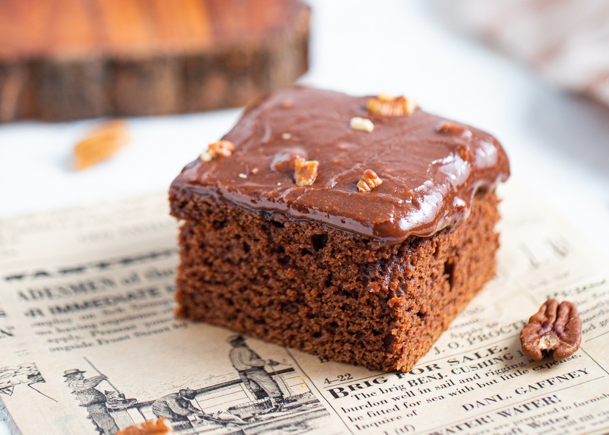 A slice of chocolate cake sitting on a newspaper