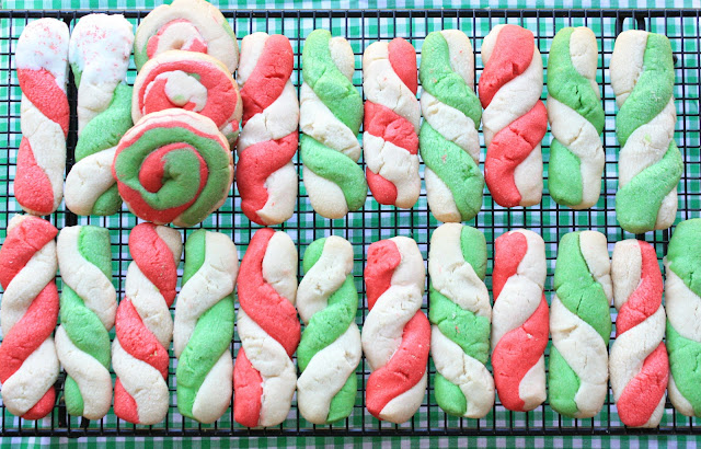 twisted red and green peppermint stick cookies stacked on a baking sheet