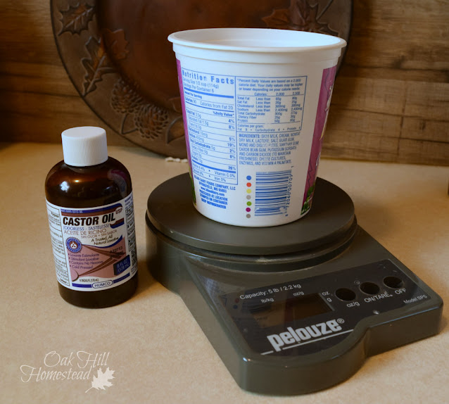 A digital scale, container and a bottle of castor oil for soap making.