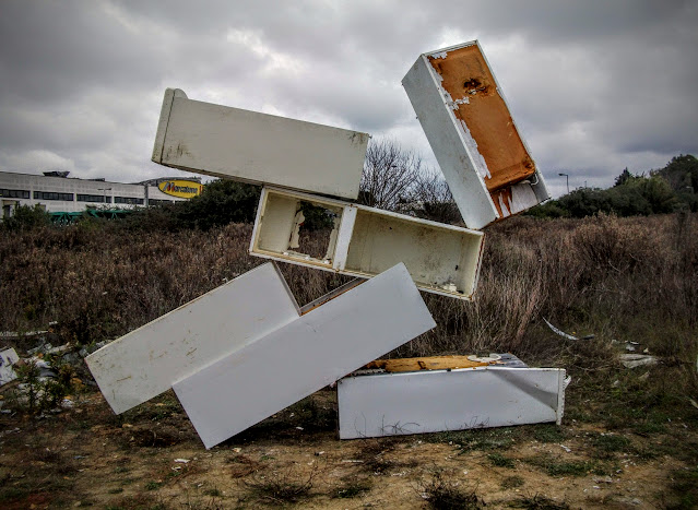 frontal view of fridge balance art with the unlikely angle of the top fridge visible against the clouds. The abandoned white goods shop is visible in the background