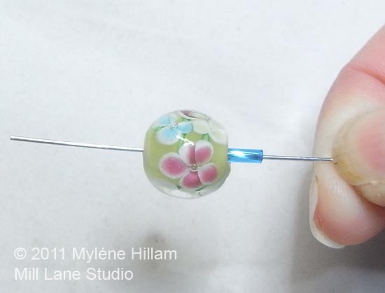 Stringing a bugle bead onto a head pin followed by a large hole bead