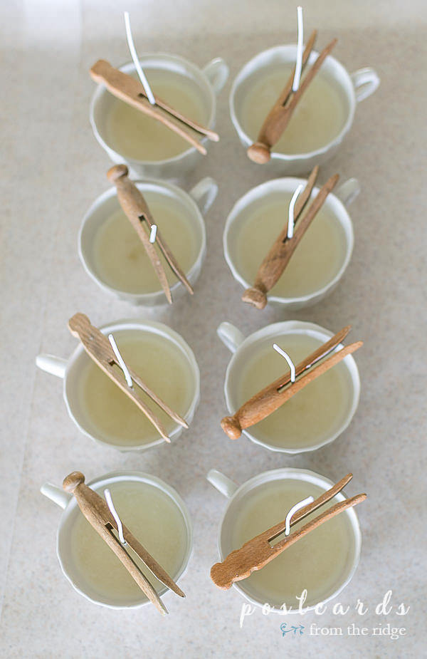 teacup candles with clothepins holding the wicks