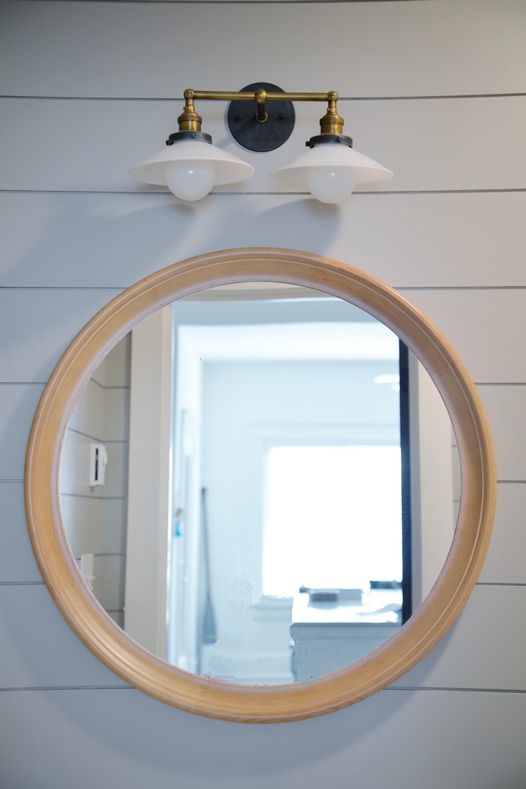 grey painted shiplap in the bathroom, round wood mirror, milk glass double sconce | Ramblingrenovators.ca