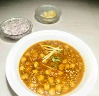 Serving garnished chole(chickpeas) with chopped onion and lemon wedges for chole recipe