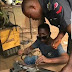 Viral photo shows a Nigerian policeman fixing his faulty gun at a roadside welder's shop