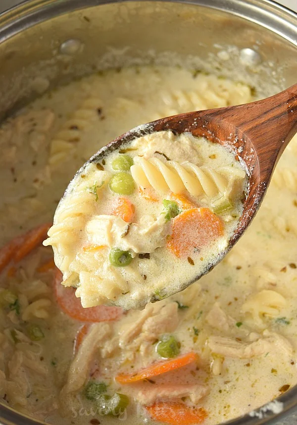 a wooden ladle with creamy chunky chicken noodle soup