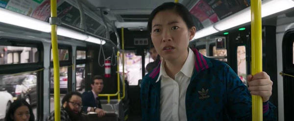 Katy (Awkwafina) watches as Shaun fights a couple of thugs, sent by his father, aboard a bus in SHANG-CHI AND THE LEGEND OF THE TEN RINGS.