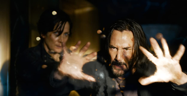 Neo (Keanu Reeves) once again stops bullets in mid-air as Trinity (Carrie-Anne Moss) looks on in THE MATRIX RESURRECTIONS.