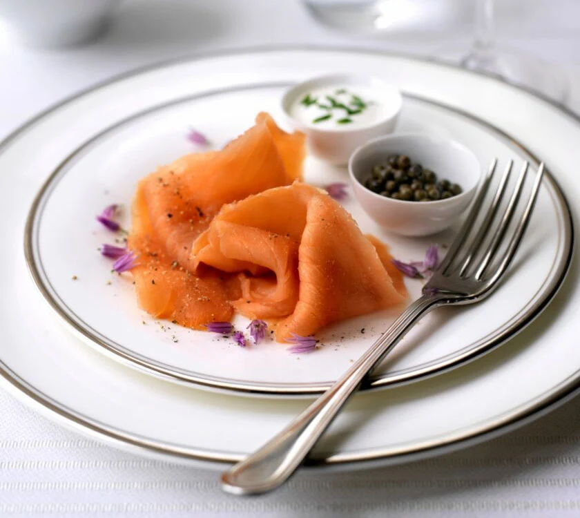 Wild hand-sliced smoked salmon on a white plate