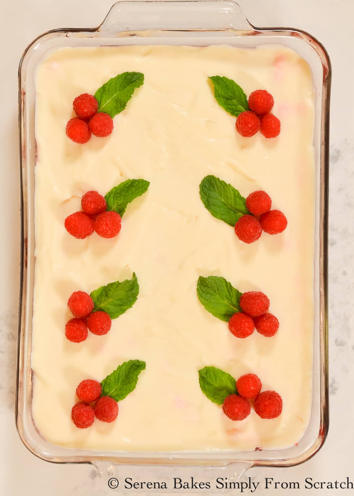 7 Up Raspberry Jello Salad with 4 sets of  3 raspberries and a mint leaf to look like a holly berry for Christmas in a clear glass 9"x13" pan space 4 down each side.