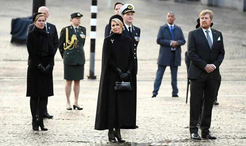 Queen Maxima wore a black wool high collar cape coat. Black leather handbag. Pearl drop earrings and diamond brooch. Gripoix earrings