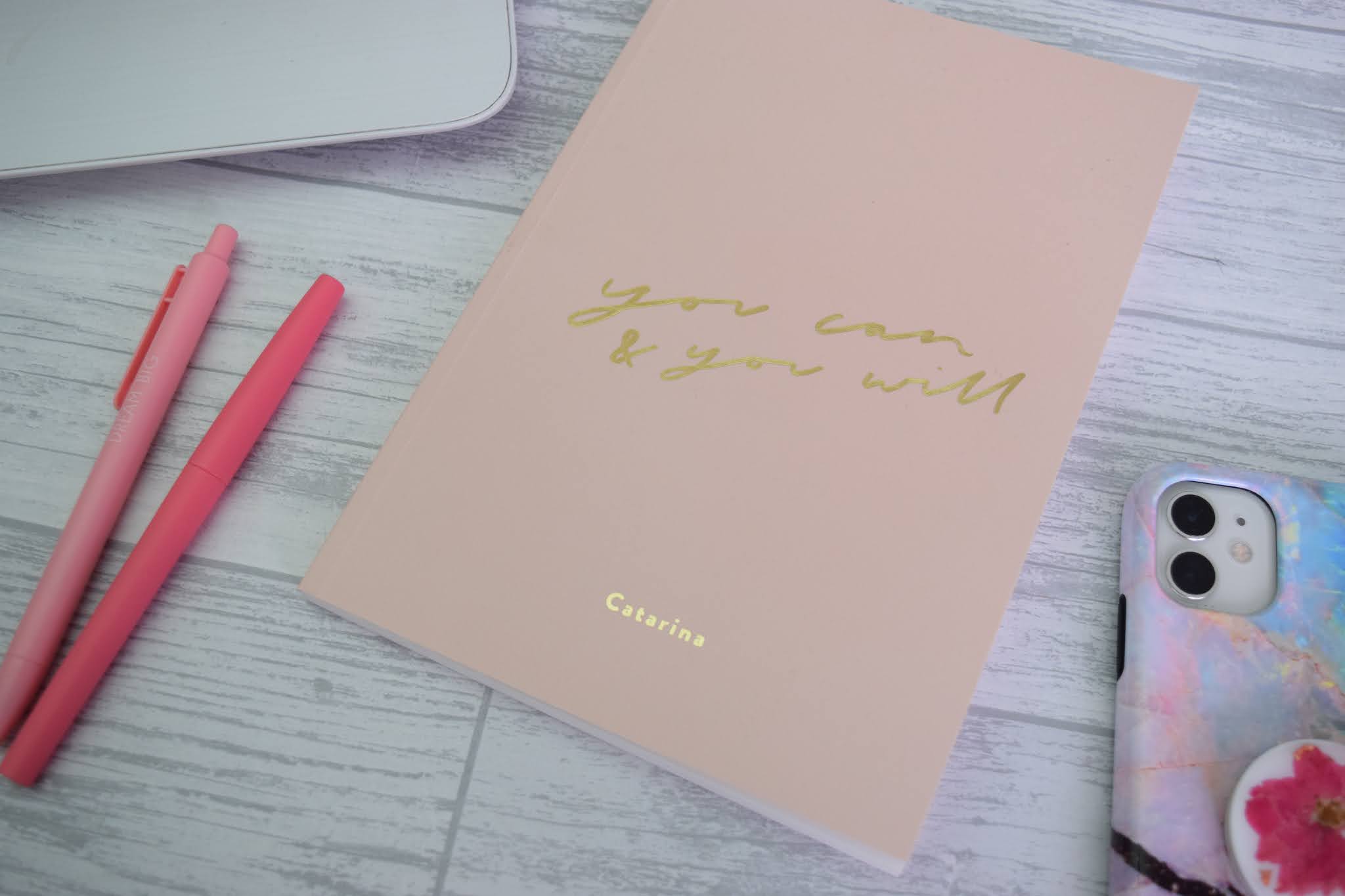 Personalised notebook with pink pens and an iPhone 11.
