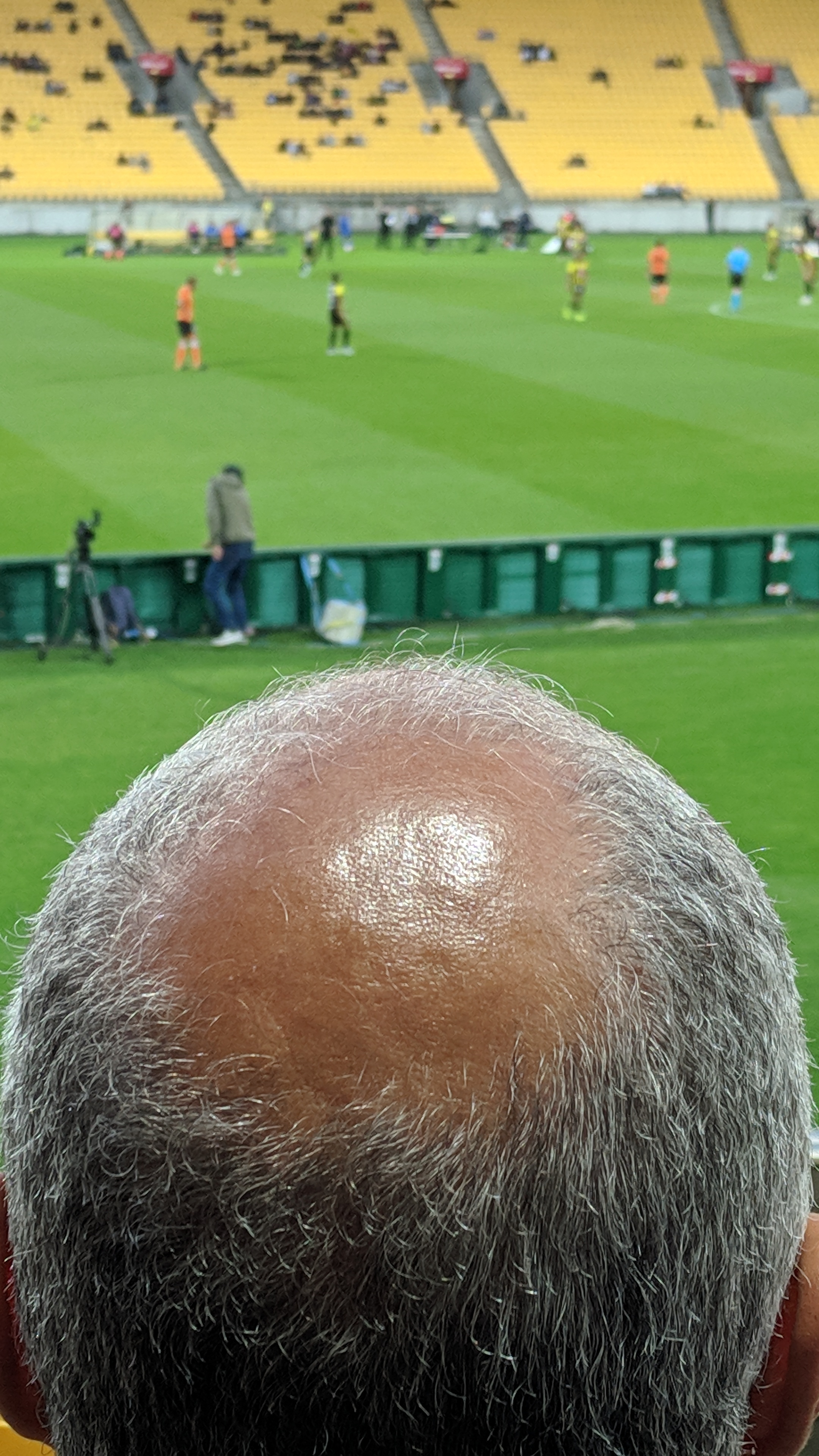 Balding head watching football in a stadium