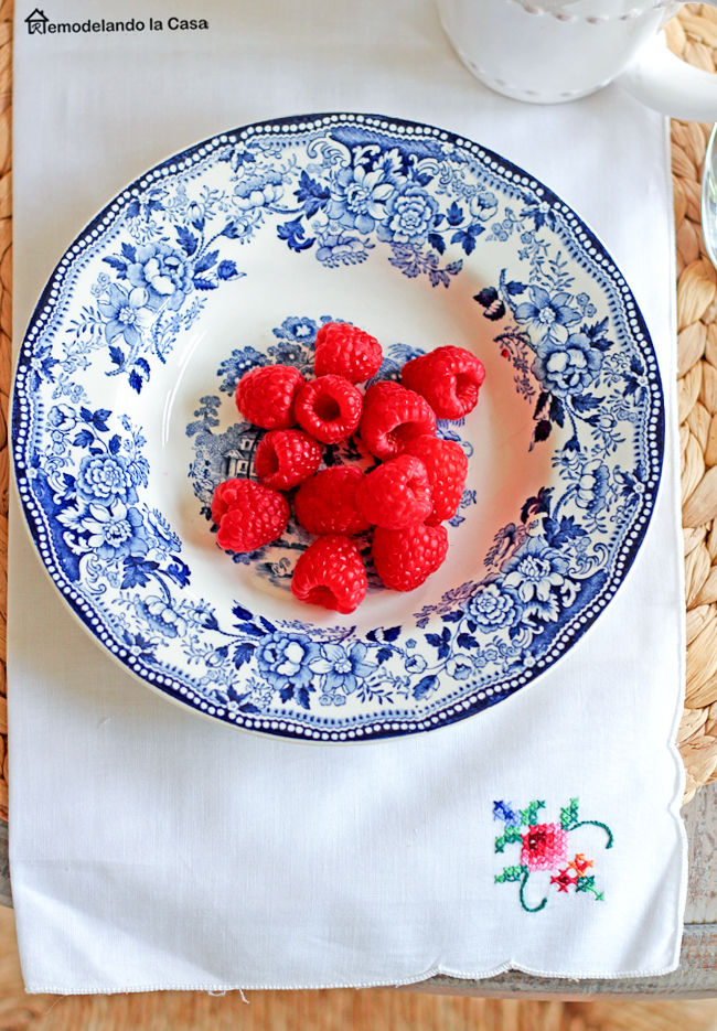 white and blue plates with raspberries and napkin with crossed stitched design