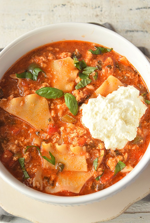 birdseye view of a white bowl with spicy lasagna soup topped with ricotta