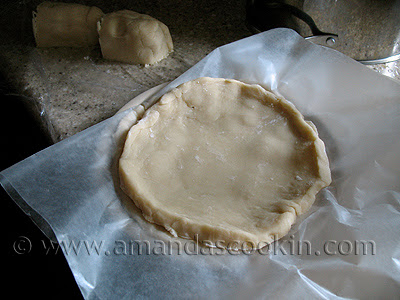 A circle of cherry hand pie dough resting on parchment paper.