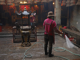 woman spraying water with a hose to clean the Man Mo Temple in Tai Po, Hong Kong