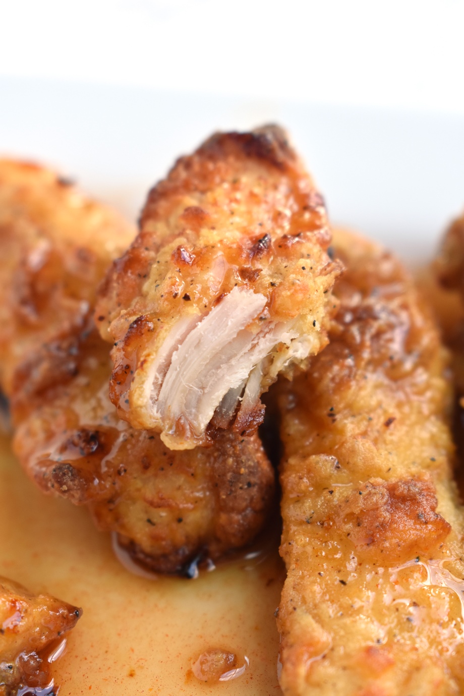 Crispy Baked Hot Honey Chicken features super crispy baked chicken strips covered in a spicy honey sauce that everyone will love! Makes a perfect appetizer or meal.