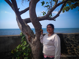 Woman Traveler Sheltering Under The Shade Tree Around Beach Barrier On A Sunny Day At The Village North Bali Indonesia