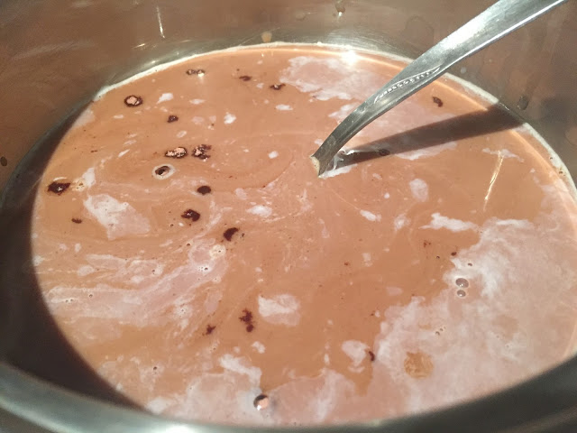 Natillas de chocolate con fresas y nata. Removiendo con una cuchara.