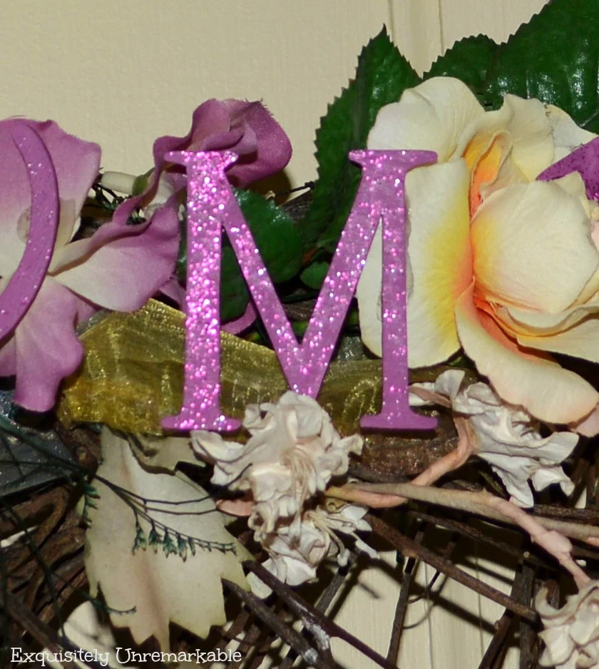 Purple glitter painted wooden M on a floral wreath