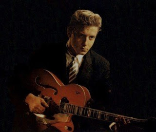 Eddy Cochran color publicity  photo playing the guitar in front of a black background