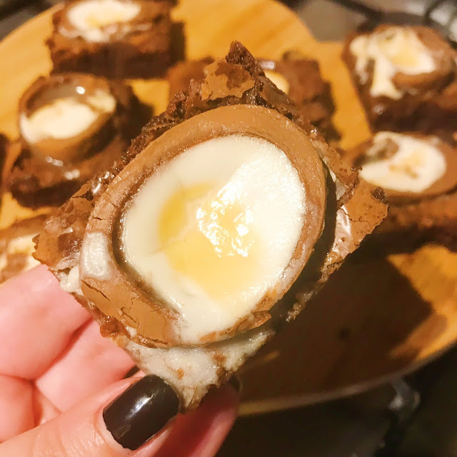 1 Creme Egg brownie held up over chopping board with creme egg brownies arranged