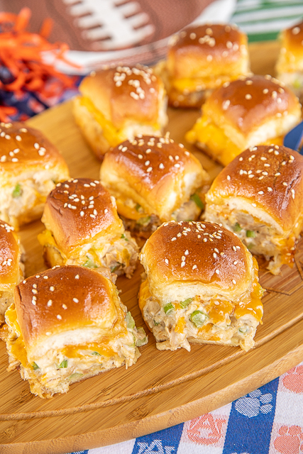 Hot Chicken Salad Sliders - my favorite chicken salad recipe and cheese sandwiched in Hawaiian rolls and topped with a sweet & savory glaze. Have mercy! Chicken, celery, Worcestershire sauce, mayonnaise, salt, pepper, Hawaiian rolls, butter, brown sugar, dijon mustard, and sesame seeds. Can assemble ahead of time and refrigerate until ready to bake. These easy baked chicken salad sandwiches that are great for parties, brunch, lunch, and dinner! #chickensalad #sandwich #sliders chicken salad sliders on a platter