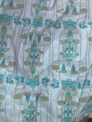 A very fine fabric with a large-scale art nouveau pattern on in grey and turquoise.