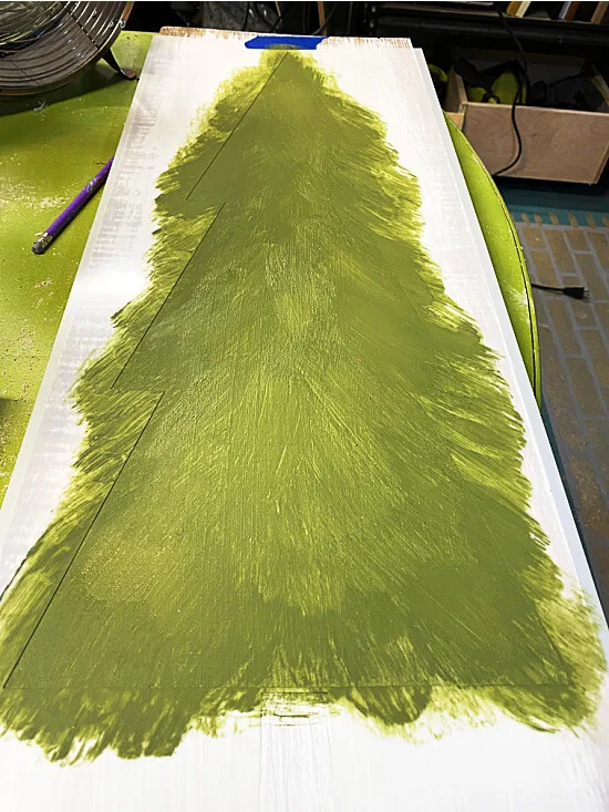 Stenciling green paint on the tree